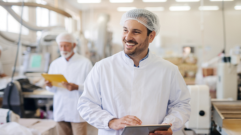 Two men wearing hairnets in a factory