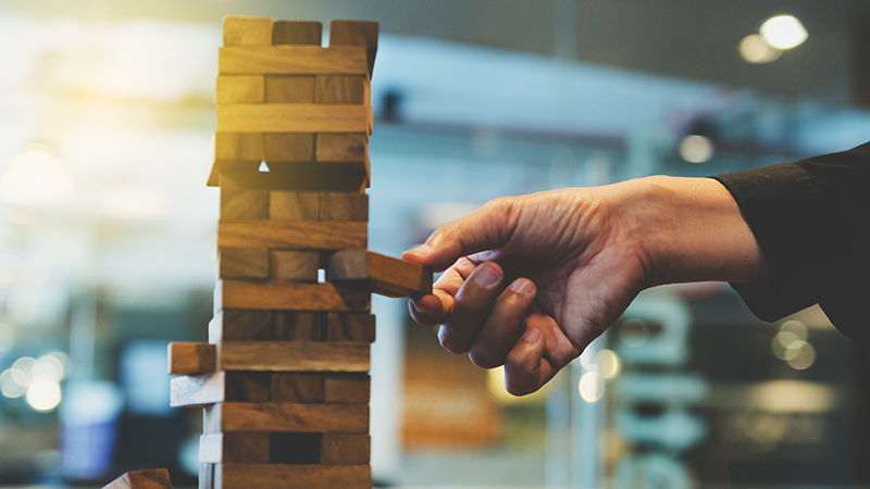 Hand pulling Jenga block out of Jenga block tower