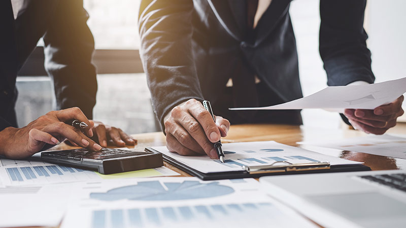 Two businessman working together on a calculator and clipboard