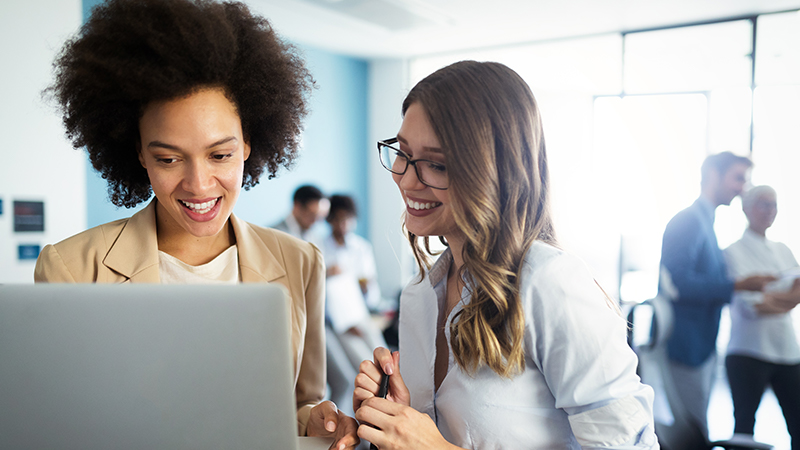Two business women working together in front of computer