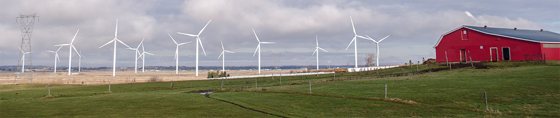 Red barn surrounded by white wind mills.