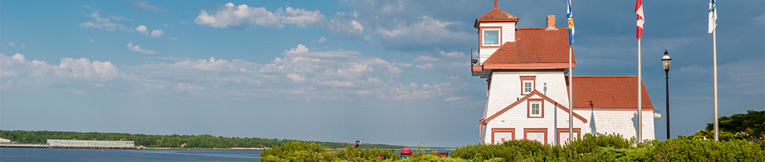 White and red lighthouse overlooking a body of water.