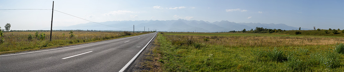 Road surrounded by fields going to the moutains.
